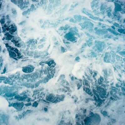Bright blue ocean water collides, creating swirls and froths.