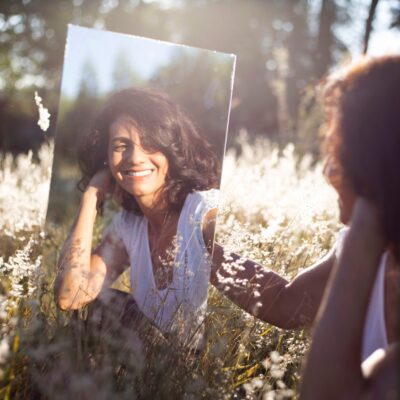 A woman smiles at herself in a mirror